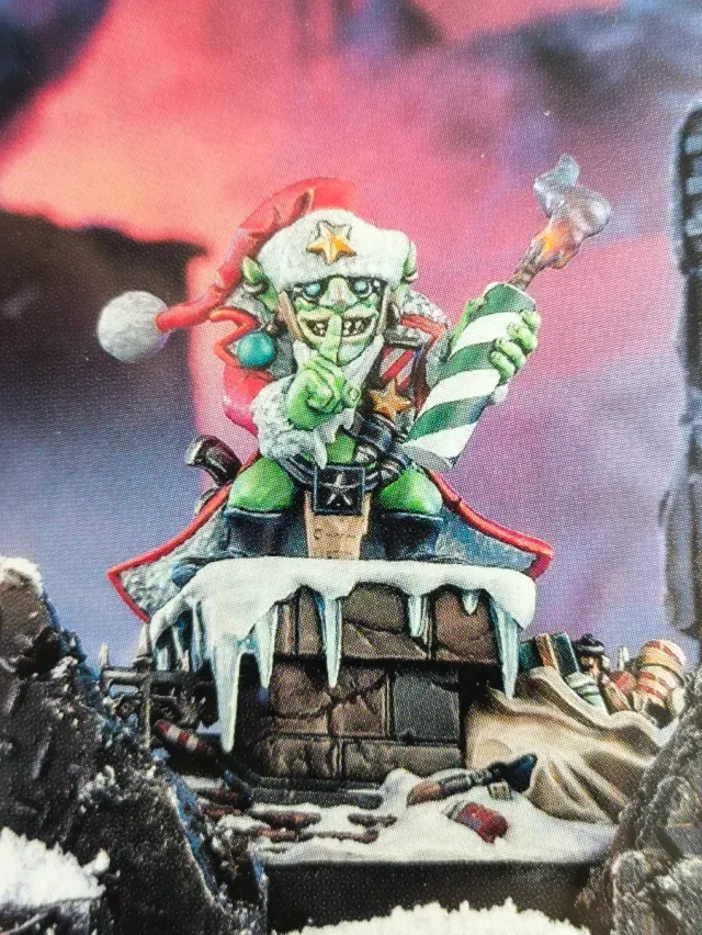 The Red Gobbo miniature, a green goblin in a Santa hat on a snowy chimney, holding a lit torch